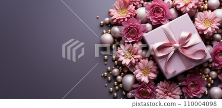 Valentin's day gift box wrapped in gold and pink paper, placed on a pile of colorful artificial flowers, against a pastel gradient background with copy space. 110004098