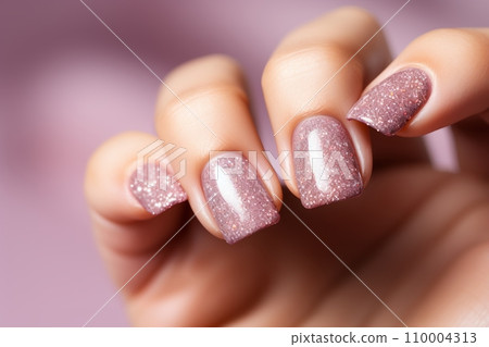 A glittery or sparkly nail polish, against a light pastel background, with a sense of glamour and luxury. The image should convey a sense of celebration and festivity. 110004313