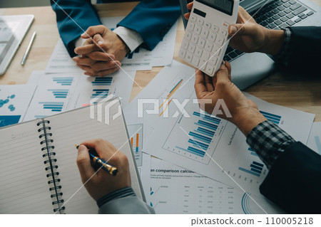Financial analysts analyze business financial reports on a digital tablet planning investment project during a discussion at a meeting of corporate showing the results of their successful teamwork. 110005218
