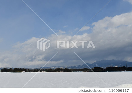 Scenery of the outskirts of Nagai town in winter on a sunny day with large clouds covering the snowy mountains Scenery of the outskirts of Nagai town in winter on a sunny day with large clouds covering the snowy mountains 110006117