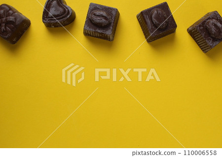 Chocolates lie on a yellow background with space for copyspace text. Background with chocolate 110006558