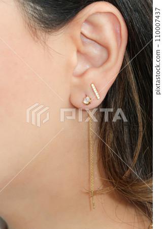 Woman wearing beautiful dangly and stud earrings with zirconia. 110007437