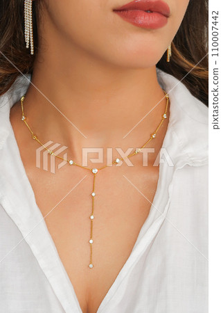 Young woman wearing a golden lariat necklace. Young woman wearing a golden lariat necklace. 110007442