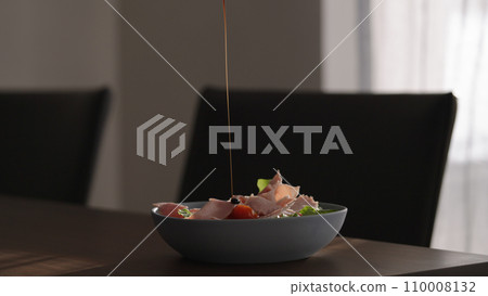 salad with tomatoes, lettuce and prosciutto cotto in blue bowl on wood table 110008132