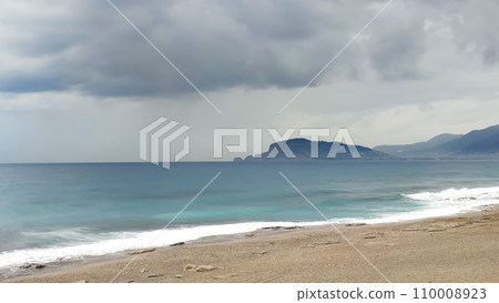 Sea coast, stormy sky over turquoise sea, view from shore. 110008923
