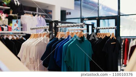 Selective focus of racks full with colorful shirt in empty modern boutique, filled with formal and casual wear design. Fashionable clothes on discount, small business commercial activity. Selective focus of racks full with colorful shirt in empty modern boutique, filled with formal and casual wear design. Fashionable clothes on discount, small business commercial activity. 110010376