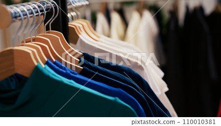 Selective focus of hangers full with colorful shirt, empty modern boutique filles with fashionable clothes. Clothing store equipped with casual and formal wear in shopping center. Fashion concept Selective focus of hangers full with colorful shirt, empty modern boutique filles with fashionable clothes. Clothing store equipped with casual and formal wear in shopping center. Fashion concept 110010381