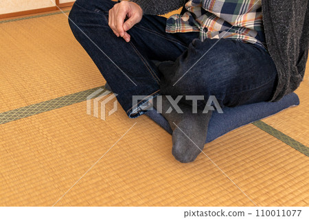 A man relaxing cross-legged in a Japanese-style room 110011077
