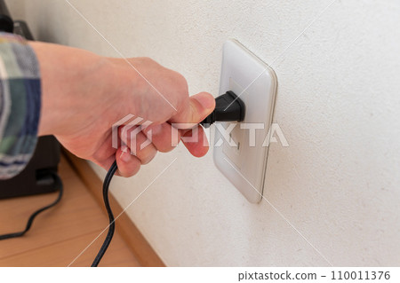 Pinch the power plug connected to the wall outlet with your fingers. 110011376