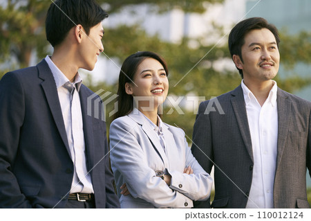 team of three asian businesspeople chatting talking conversing outdoors 110012124