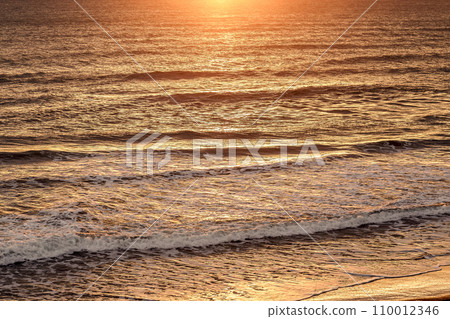 The ocean dyed golden by the reflection of sunrise 110012346