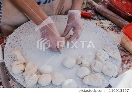 woman's hands making qutab or chebureki with a rolling pin and minced meat onion in dough for culinary concepts related to Azerbaijani, Tatar and Greek cuisine, as well as empanadas in Latin America. woman's hands making qutab or chebureki with a rolling pin and minced meat onion in dough for culinary concepts related to Azerbaijani, Tatar and Greek cuisine, as well as empanadas in Latin America. 110013367