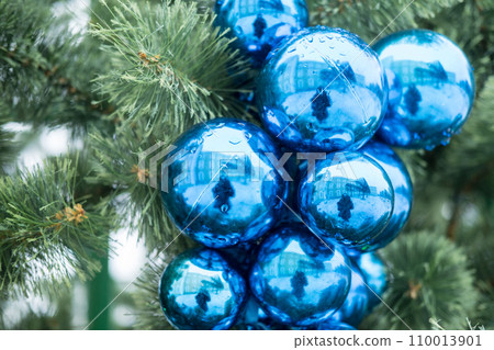 Blurred reflection of woman holding a camera in Christmas ball on Christmas tree. 110013901