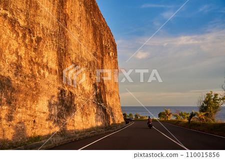 The cliff overhangs along the road to the ocean at sunset. 110015856