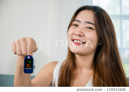 Asian young woman using medical oximeter equipment to measure pulse oxygen saturation on sofa in living room at home, Self healthcare with corona virus pandemic, medical healthcare Asian young woman using medical oximeter equipment to measure pulse oxygen saturation on sofa in living room at home, Self healthcare with corona virus pandemic, medical healthcare 110015886