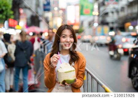 Young asian woman traveller standing and drinking coconut water 110015926