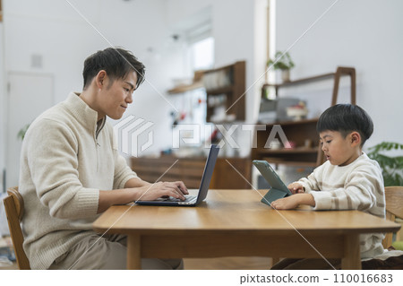 An elementary school boy operating a tablet PC and his father working on a laptop An elementary school boy operating a tablet PC and his father working on a laptop 110016683