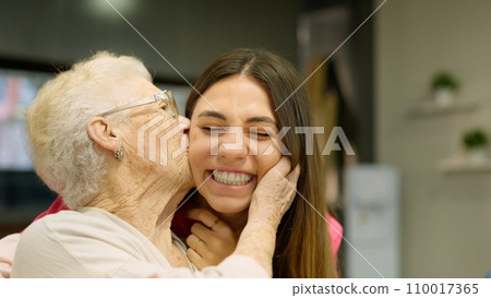 Endearing image of a grandmother kissing her granddaughter Endearing image of a grandmother kissing her granddaughter 110017365