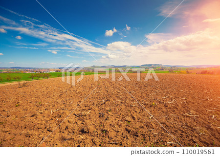 Arable field with beautiful sky and village on a horizon. Springtime 110019561