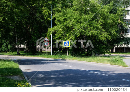 Sign of the pedestrian crossing on the road among the green forest in summer 110020484