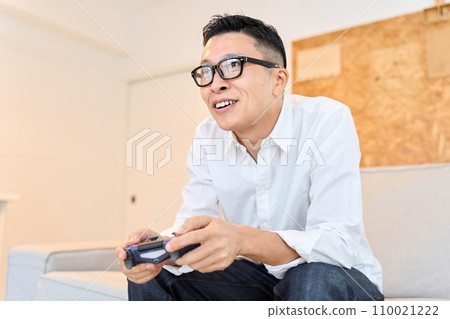Asian man playing games in the living room 110021222