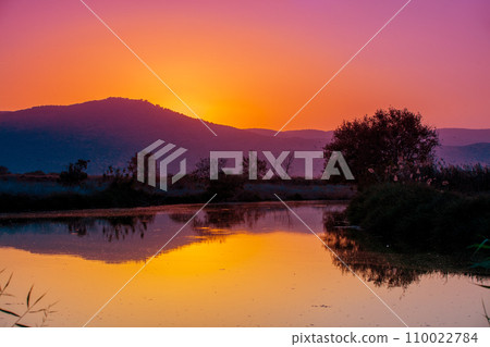 Mountain landscape in the evening. Beautiful lakeshore against mountains. The Hula Valley in northern Israel at sunset 110022784
