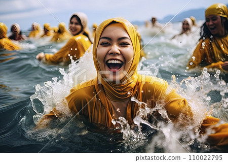 Smiling Muslim woman with hijab joyfully enjoys a fully clothed bath in the sea 110022795