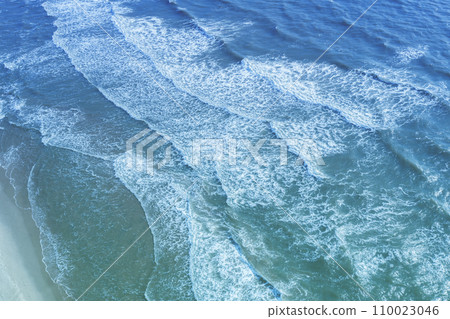Seascape. Sandy beach. Sea waves roll onto the sandy beach. Top diagonal view. Abstract nature landscape background 110023046