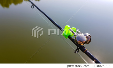 Swing fishing. Rods for carp fishing with a signaling close-up. Kind of pod. Fishing for carp on the background of the lake. The fisherman catches carp Swing fishing. Rods for carp fishing with a signaling close-up. Kind of pod. Fishing for carp on the background of the lake. The fisherman catches carp 110023998