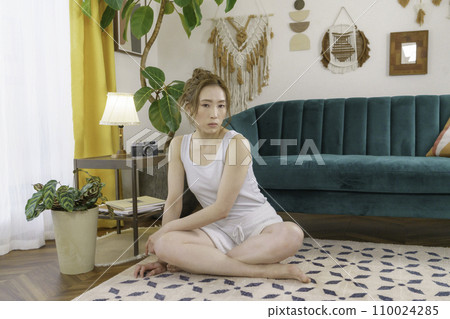 坐在客廳地板上的一位年輕棕髮女子的肖像 110024285