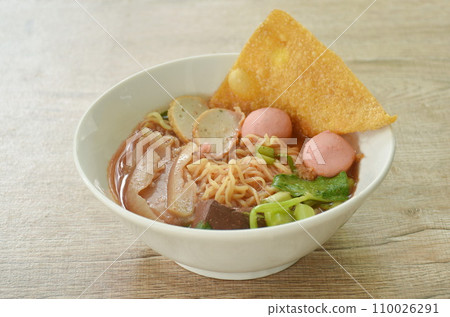 Chinese yellow egg noodles with fish ball and chop pork in red soup on bowl Chinese yellow egg noodles with fish ball and chop pork in red soup on bowl 110026291