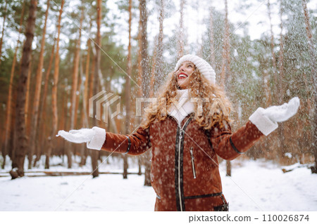 Beautiful woman standing among snowy trees and enjoying first snow. Holidays, rest, travel concept. 110026874
