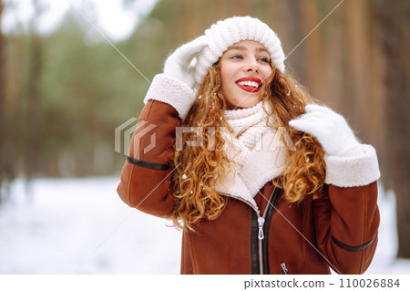 Beautiful woman standing among snowy trees and enjoying first snow. Holidays, rest, travel concept. Beautiful woman standing among snowy trees and enjoying first snow. Holidays, rest, travel concept. 110026884