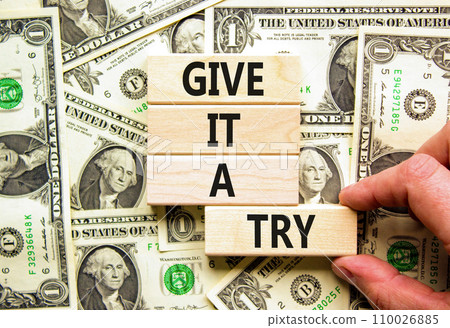 Give it a try symbol. Concept word Give it a try on beautiful wooden block. Dollar bills. Beautiful background from dollar bills. Businessman hand. Business give it a try concept. Copy space. 110026885