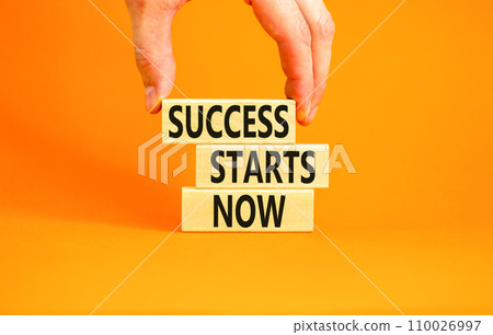 Success starts now symbol. Concept word Success starts now on beautiful wooden block. Businessman hand. Beautiful orange table background. Business motivational success starts now concept. Copy space. 110026997