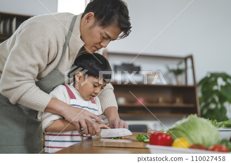 父母和孩子做飯，父親幫助男孩切菜 110027458