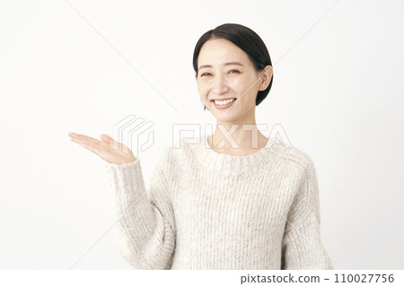 Middle-aged woman pointing to the left side with her palm, white background Middle-aged woman pointing to the left side with her palm, white background 110027756