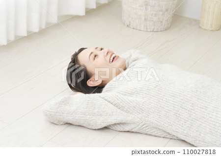 Middle-aged woman lying on her back on the flooring Middle-aged woman lying on her back on the flooring 110027818