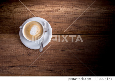 Cup of freshly brewed aromatic cappuccino standing on a wooden table 110028165