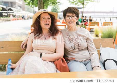 Happy mature mother and her adult daughter enjoying in conversation while spending Mother's day together in a cafe 110028803
