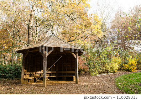 Autumn trees and wooden huts in a park under a blue sky with clouds floating in Richmond Park on the outskirts of London 110029315