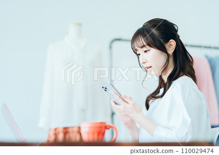 A woman looking at her smartphone at work A woman looking at her smartphone at work 110029474