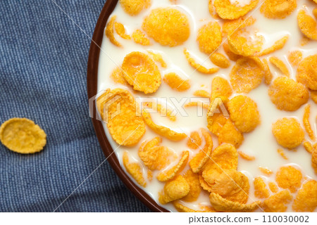 Crispy corn flakes with milk on a blue table. Top view 110030002