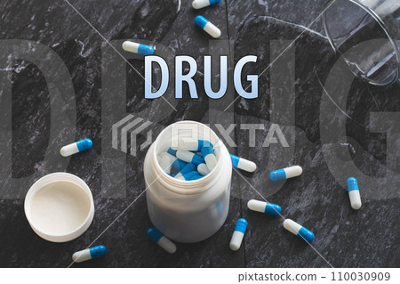 The inscription drug on the background of pills on a black table. The inscription drug on the background of pills on a black table. 110030909