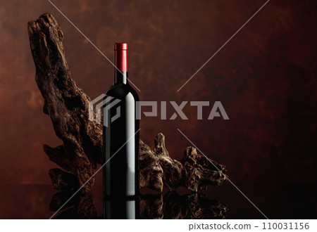 Bottle of red wine with an old weathered snag. 110031156