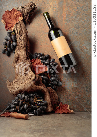 Bottle of red wine with blue grapes on a rusty background. 110031158