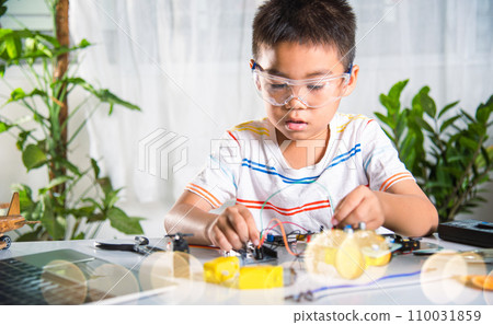 Asian kid boy plugging energy and signal cable to sensor chip with Arduino robot car, Little child remotely learn online with car toy, STEAM education AI technology course school learning lesson 110031859
