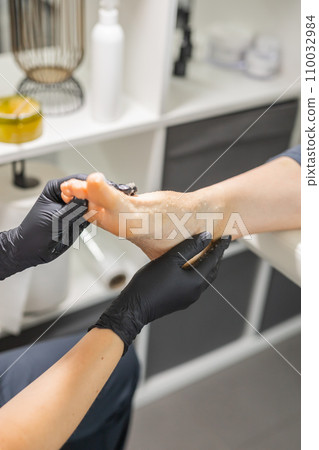 Woman doing foot peeling in pedicure SPA salon. Sugar scrub and relax beauty procedure Woman doing foot peeling in pedicure SPA salon. Sugar scrub and relax beauty procedure 110032984