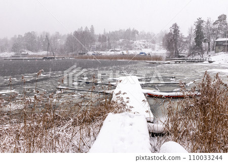 Landscape. Half frozen lake, snow coated trees. Boat pier in winter. winter view of the frozen lake. 110033244