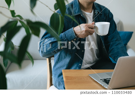 Middle-aged man operating a computer at home Middle-aged man operating a computer at home 110033480